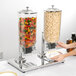 A woman using a Choice double canister cereal dispenser to fill a plate with food.