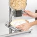 A person using a Choice double canister cereal dispenser to pour cereal into a bowl.