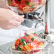 A person's hand pouring gummy bears into a Choice cereal dispenser.