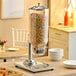 A single canister cereal dispenser with a clear container and metal base, filled with cereal.