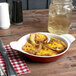 A bowl of potatoes and cheese in a red and white enamel round pan.
