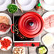 A red GET Heiss cast aluminum dutch oven with food on top on a table with other food.