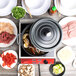 A table with a GET gray enamel coated dutch oven with food in it next to plates of food.