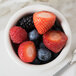 A Tuxton eggshell fluted ramekin filled with fruit with a spoon.