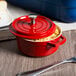 A red and white enamel coated cast aluminum GET bistro pot with a lid.