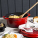 A red GET Heiss cast aluminum dutch oven with food in it and a wooden spoon.