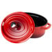 A red oval Dutch oven with a black lid with a red knob.