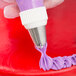 A person using an Ateco pastry bag with a Swirl Top piping tip to pipe purple and white frosting on a cake.