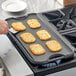 A person using Valor cast iron griddle to cook food on a table.