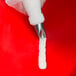 A hand holding a white Ateco curved petal piping tip.