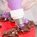 A person using an Ateco pastry bag to decorate a cake.