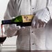 A man wearing white Henry Segal waiter's gloves pouring wine into a glass.