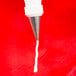 A close-up of a white Ateco Cross-Top Piping Tip being used to pipe white icing.