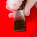 A person in gloves holding a plastic bag of chocolate.