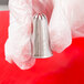 A hand holding an Ateco silver closed star piping tip.