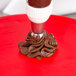 A chocolate cake being decorated with an Ateco Russian ball tip piping tip on a pastry bag.