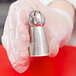 A person in gloves holding a stainless steel ball with a metal cup on the end.