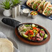 A Valor oval cast iron fajita skillet with steak and vegetables on a table.