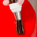 A person's hand using an Ateco closed star piping tip and pastry bag to pipe chocolate frosting on a cake.