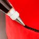 A pastry bag with a closed star piping tip and chocolate frosting being piped onto a cake.