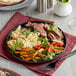 A white plate with a Valor Pre-Seasoned Cast Iron Fajita Skillet on it with meat, vegetables and rice.