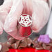 A hand holding a metal Ateco Russian piping tip with red designs.