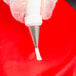 A hand using a silver Ateco closed star piping tip on a pastry bag.