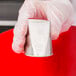 A hand in a white glove holding a silver Ateco rose piping tip.