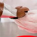 A person using an Ateco rose piping tip to pipe brown frosting onto a pastry.