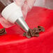 A person using an Ateco pastry bag with a closed star tip to decorate a cake.