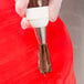 A person using an Ateco pastry bag to pipe chocolate frosting on a cake.