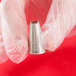 A person holding an Ateco drop flower piping tip.