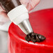 A person using an Ateco Swirl Top piping tip to decorate a cake with a pastry bag.