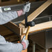 A hand in a Cordova Machinist glove with gray palm coating holding a hammer to nail a piece of wood.