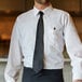 A man wearing a Henry Segal black tie and white shirt.