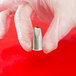 A hand in gloves holding an Ateco curved petal piping tip nozzle.