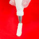 A hand holding a pastry bag with white frosting and a swirl design using an Ateco swirl top piping tip.