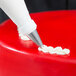 A person using an Ateco swirl top piping tip to decorate a red cake with a pastry bag.
