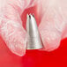 A hand holding a silver Ateco swirl top piping tip.
