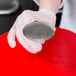 A person in gloves holding a silver flat metal flower nail.