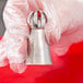 A person using an Ateco Russian ball tip piping tip to decorate pastries on a counter.