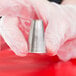 A hand holding an Ateco drop flower piping tip.