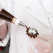 A person in white gloves using an Ateco domed flower nail to decorate a pastry.