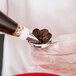 A person holding an Ateco stainless steel flower nail above a pastry bag.