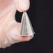 A hand holding a metal Ateco ruffle piping tip.
