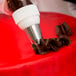 A person using an Ateco pastry bag with a closed star piping tip to pipe chocolate.