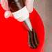 A person using an Ateco swirl top piping tip on a pastry bag to decorate a cake.