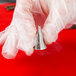 A hand holding a silver Ateco notched ruffle piping tip.