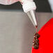 A pastry bag with the Ateco 17 Open Star piping tip on a red cake.