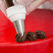 A person using an Ateco swirl top piping tip to decorate a red cake.